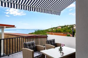 a patio with a table and chairs on a balcony at Villa Nela Apartments in Crikvenica