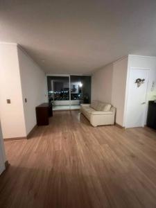 een lege woonkamer met een bank en houten vloeren bij Apartamento Mirador Lo Campino in Santiago