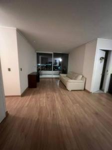 een woonkamer met een witte bank en houten vloeren bij Apartamento Mirador Lo Campino in Santiago