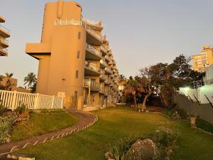 a building with a grass yard next to a building at Beachfront apartment in Ballito! Casablanca in Ballito