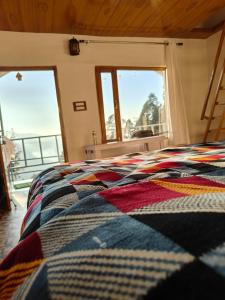 um quarto com uma cama com um cobertor colorido em HimWanderer Camps & Cottages Pangot em Nainital