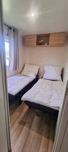 twee bedden in een kleine kamer met houten vloeren bij Ferienhaus Chalet Ferienpark Lauwersoog NL in Lauwersoog