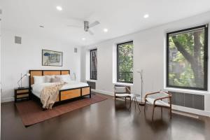 a bedroom with a bed and two chairs and windows at Chelsea Canvas II by RoveTravel Large 3BR Duplex in New York