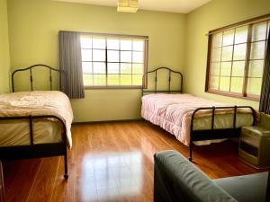 a bedroom with two beds and a couch and windows at Myoko Casa in Myoko