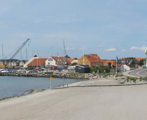 a road next to a body of water with houses at Enø / Karrebæksminde, Strandrylevej 31 in Karrebæksminde