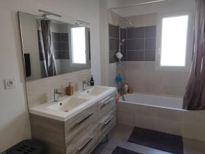 een badkamer met een wastafel, een bad en een spiegel bij Villa Darna avec piscine au calme in Saint-Sulpice-et-Cameyrac