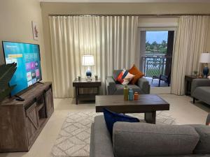 a living room with a television and a couch and a table at Canal Front Comfort (Dock slip available) in Freeport