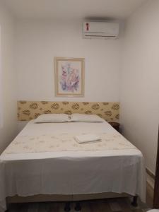 um quarto com uma cama grande e um cobertor branco em Hospedaria Ilhéus 04 em Ilhéus