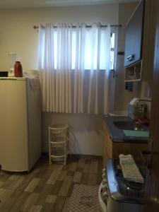 a small kitchen with a refrigerator and a sink at Hospedaria Ilhéus 04 in Ilhéus