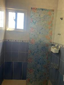 y baño con ducha y pared de azulejos florales. en Paraíso del mar, en Mandinga