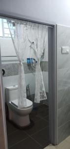 a bathroom with a toilet with curtains on it at Pantai Remis Homestay 118A in Pantai Remis