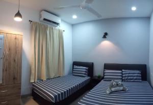 a bedroom with two beds and a teddy bear sitting on the bed at Pantai Remis Homestay 118A in Pantai Remis
