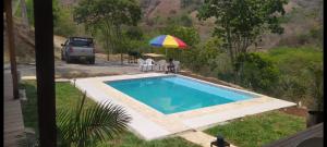 a pool with a umbrella and two people sitting under a umbrella at Villa del sueño in Olaya