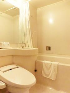 a white bathroom with a toilet and a bath tub at Green Hotel Kitakami in Kitakami