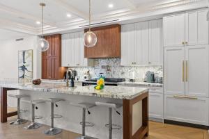 a kitchen with white cabinets and a large island with bar stools at Riverside by Rove Travel 7BR Modern Townhouse in New York