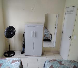 a white refrigerator in a room with a bedroom at Acomodações Casa 1 in Cananéia