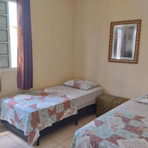 een slaapkamer met 2 aparte bedden en een spiegel bij Acomodações Casa 1 in Cananéia