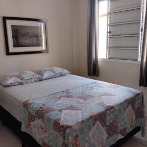 een slaapkamer met een bed met een quilt bij Acomodações Casa 1 in Cananéia