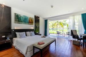 a bedroom with a large bed and a large window at TUI BLUE Nam Hoi An Resort in Tam Kỳ