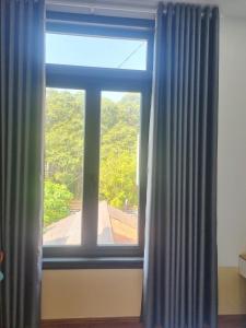 a window with blue curtains in a room at Khôi Đại Hotel - gần sân bay Buôn Ma Thuột, near Buon Ma Thuot Airport in Buon Ma Thuot
