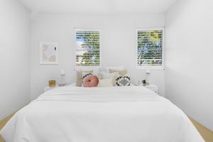 a white bedroom with a large white bed with a pink orb on it at A Tropical Family Oasis in Sunshine Beach in Sunshine Beach +20 photos