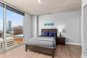 ein Schlafzimmer mit einem Bett und einem großen Fenster in der Unterkunft Luxury 2BR Penthouse in Downtown GR in Grand Rapids