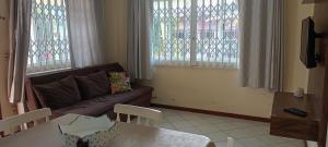 sala de estar con sofá, mesa y ventanas en Parada de Bombas Apartamentos, en Bombinhas