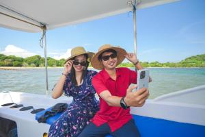 un homme et une femme prenant une photo sur un bateau dans l'établissement Samawa Seaside Resort, à Sumbawa Besar