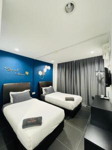 een hotelkamer met 2 bedden en een blauwe muur bij Halo Rooms Hotel in Wakaf Baharu