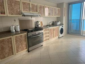 a kitchen with a stove and a dishwasher at Ft 30f R2 SeaView Room at Beach with separate bath in Ajman 