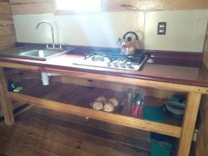 a kitchen counter with a sink and a stove at CABAÑA MINCHY in Mazamitla
