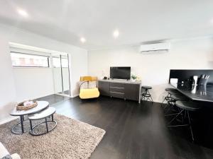 d'un salon avec une télévision et une chaise jaune. dans l'établissement New Lynn Dream guest house, à Auckland