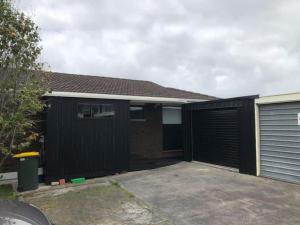 a garage with a black fence and a building at New Lynn Dream guest house in Auckland