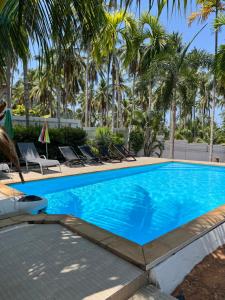 una piscina con sillas y palmeras en Khaolak Hillside Villa en Khao Lak