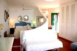 a bedroom with a white bed and a spiral staircase at La Bergerie Isolabella sea view B & B in Taormina