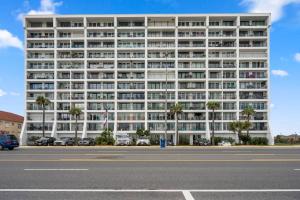 a large white building with palm trees in front of a parking lot at Bello condominio con vista al mar, jacuzzi interno in Galveston