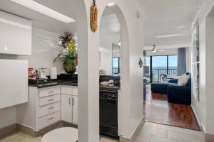 a kitchen with white cabinets and a living room at Bello condominio con vista al mar, jacuzzi interno in Galveston