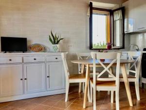 eine Küche mit einem Tisch und Stühlen sowie einem TV in der Unterkunft Unabhaengige Wohnung in Calasetta mit Grill, Terrasse und Garten in Calasetta