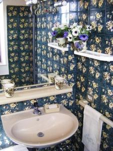 ein Badezimmer mit einem Waschbecken und Blumen an der Wand in der Unterkunft Unabhaengige Wohnung in Calasetta mit Grill, Terrasse und Garten in Calasetta