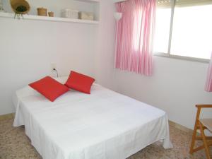 1 dormitorio con 1 cama blanca y 2 almohadas rojas en Apartamento Playa de Gandía, 3 dormitorios, 7 personas - ES-314-8, en Gandía
