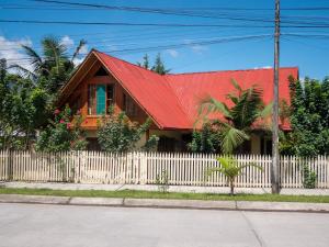 een huis met een rood dak en een wit hek bij Hospedaje Cattleya in Oxapampa