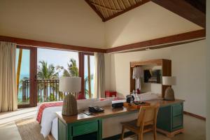 a bedroom with a desk and a bed with a view at Kalandara Resort Lombok in Senggigi 