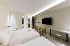 una camera d'albergo con letto, scrivania e TV di MUTE HOTEL a Busan