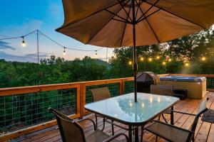 una mesa y sillas en una terraza con sombrilla en Ultimate Summer Escape! Cabin-Hot Tub-Cozy-Views-Minutes2Fun en Sevierville