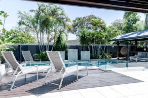 a group of chairs and a glass table on a patio at The Seaglass Villa Private Pool and Sauna in Sunshine Beach