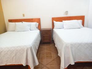 two beds in a room with white sheets at Hospedaje casa Yuca in Valladolid