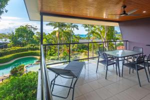 a balcony with a table and chairs and a view of a pool at Anchorage Apartments on Hamilton Island by HIHA in Hamilton Island