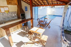 balcón con mesa, sillas y piscina en Apto Taperapuan 2 quartos com piscina perto praia, en Porto Seguro