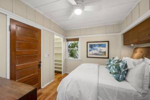 1 dormitorio con cama blanca y puerta de madera en Cute Hillcrest cottage, en San Diego