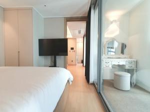 ein Schlafzimmer mit einem großen weißen Bett und einem Spiegel in der Unterkunft Elbon The Stay Haeundae 엘본더스테이 해운대 in Busan
